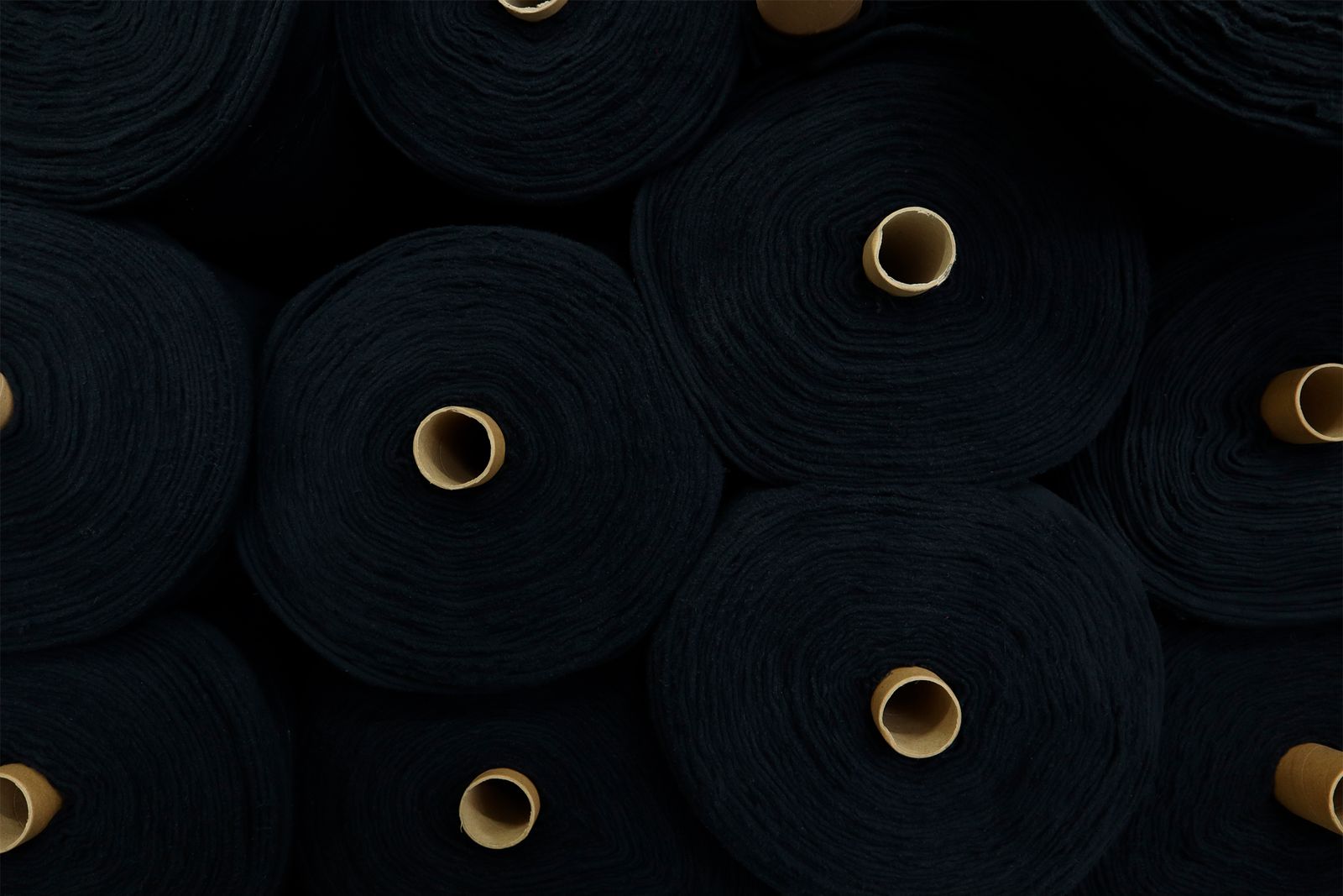 Navy-dyed rolls stacked after finishing — clean, consistent output