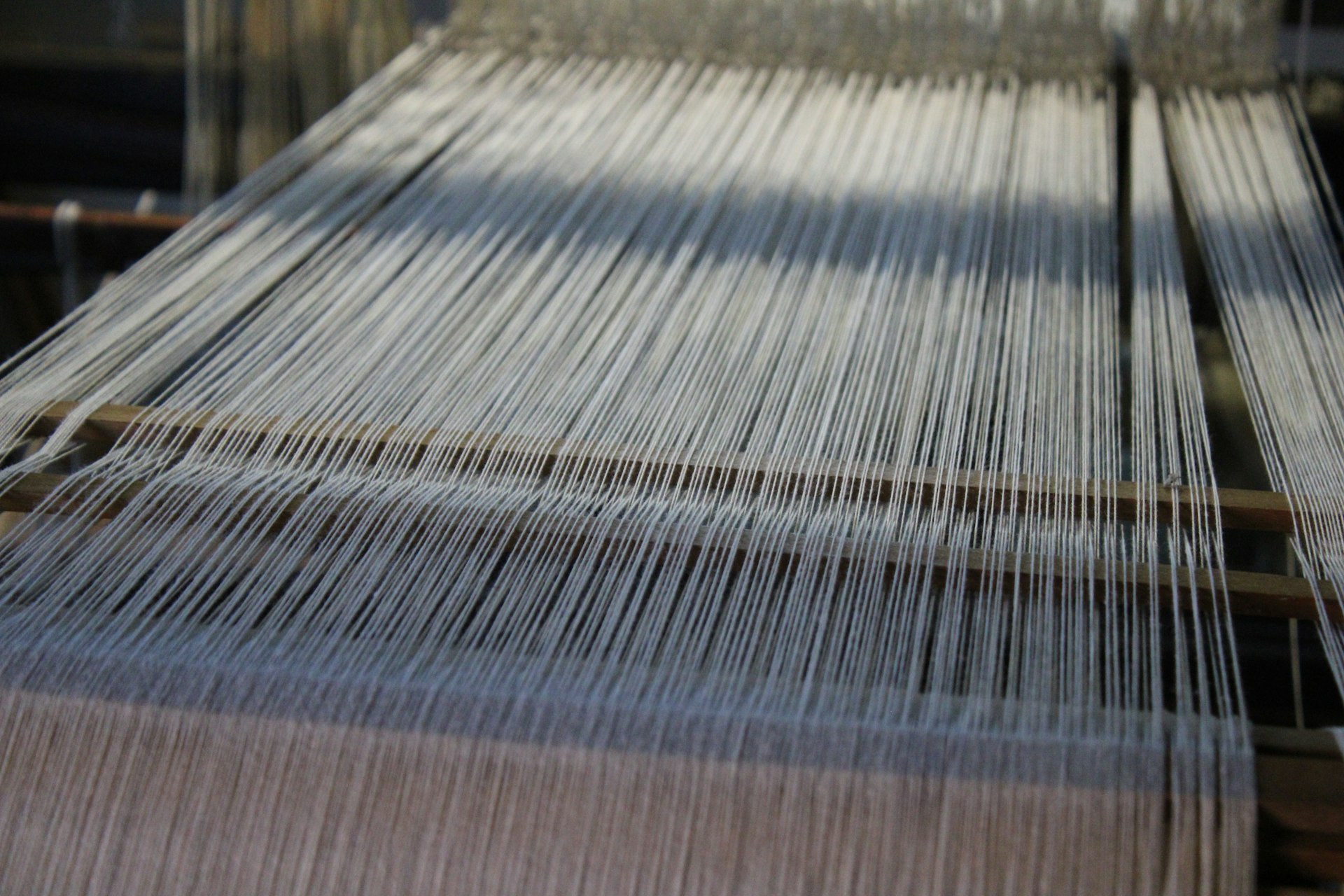 Warp threads under tension on a loom inside the Yoga Fabrics weaving mill in Erode